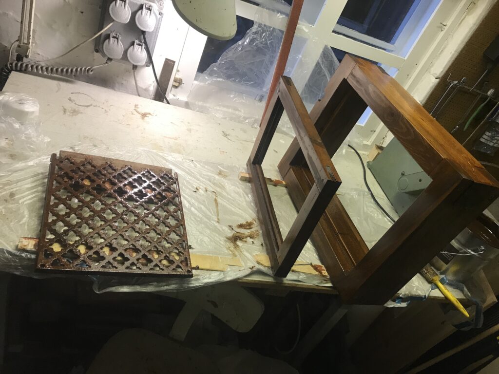 Mellanstrykning i kulören bränd umbra (brun) av träkarm, träbåge och gjutjärnsventilgaller